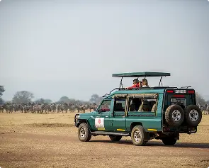 Safari vehicle crossing open African grasslands
